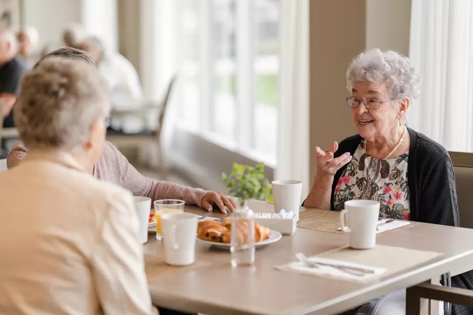 Senior residents having a pleasant conversation at the dinning table while enjoying a cup of coffee