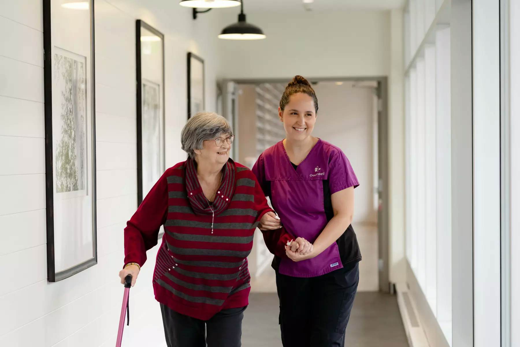 Chartwell Care staff  helping senior resident walk by holding her hand