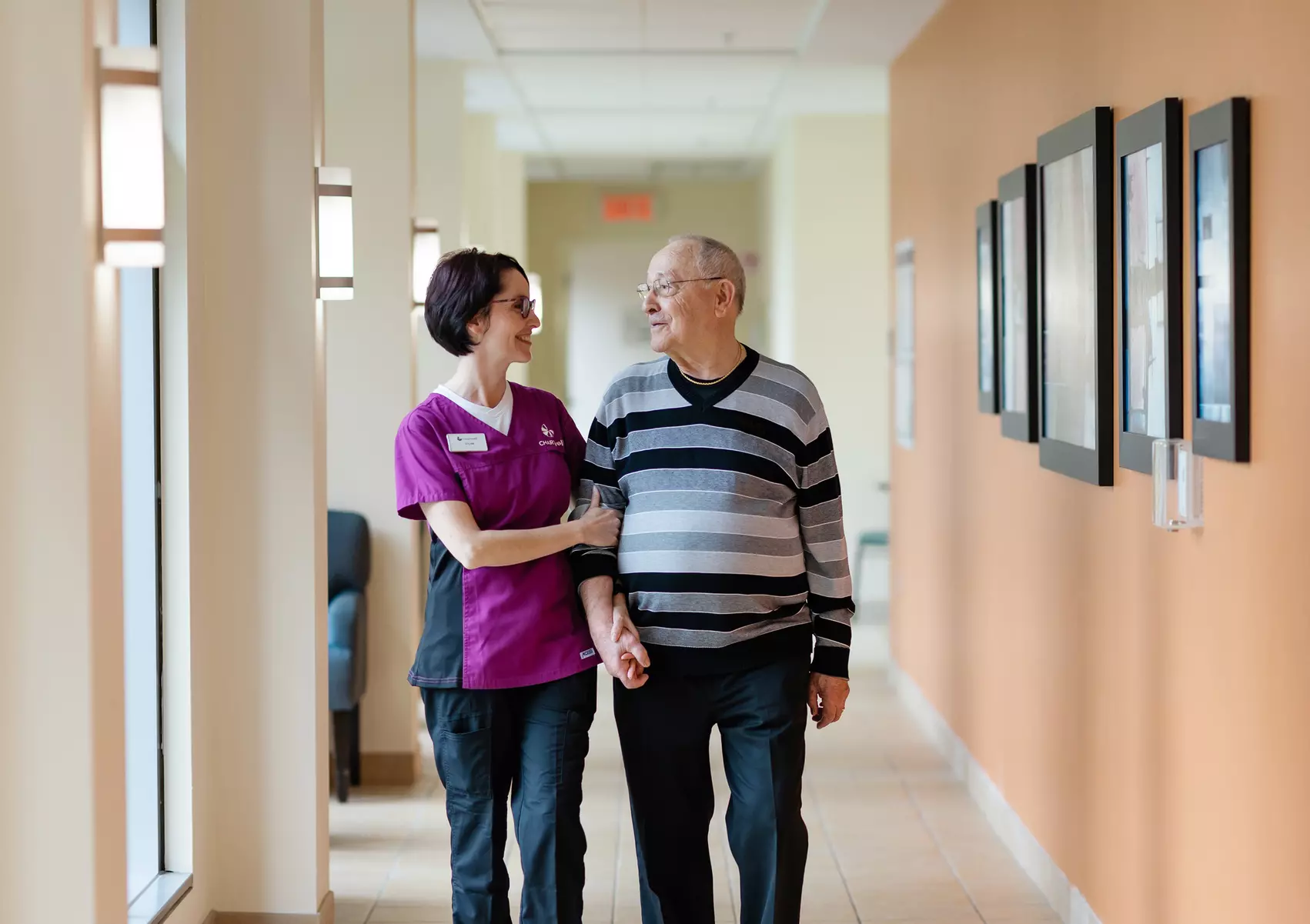 Chartwell care support staff helping a senior resident walk along the corridor