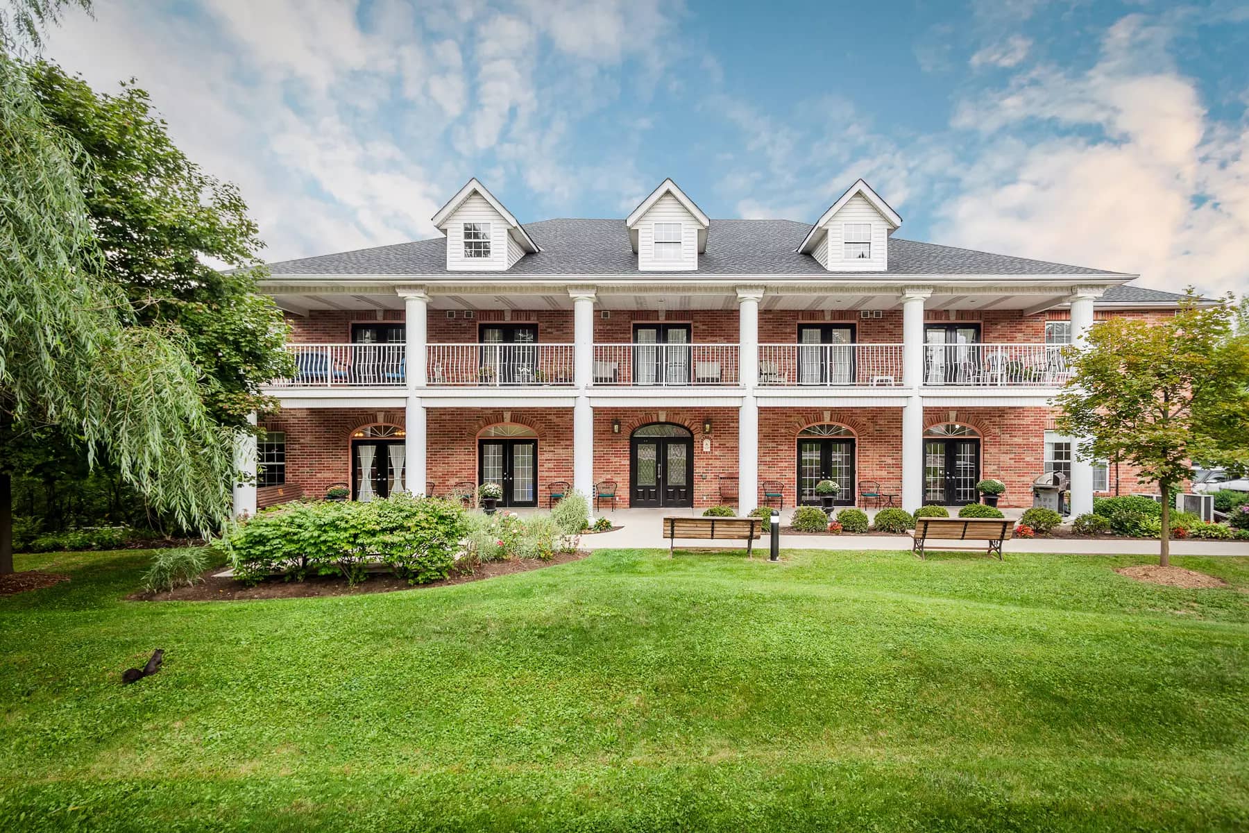 Gorgeous front of building with gardens and patio at Chartwell Georgian Retirement Residence.