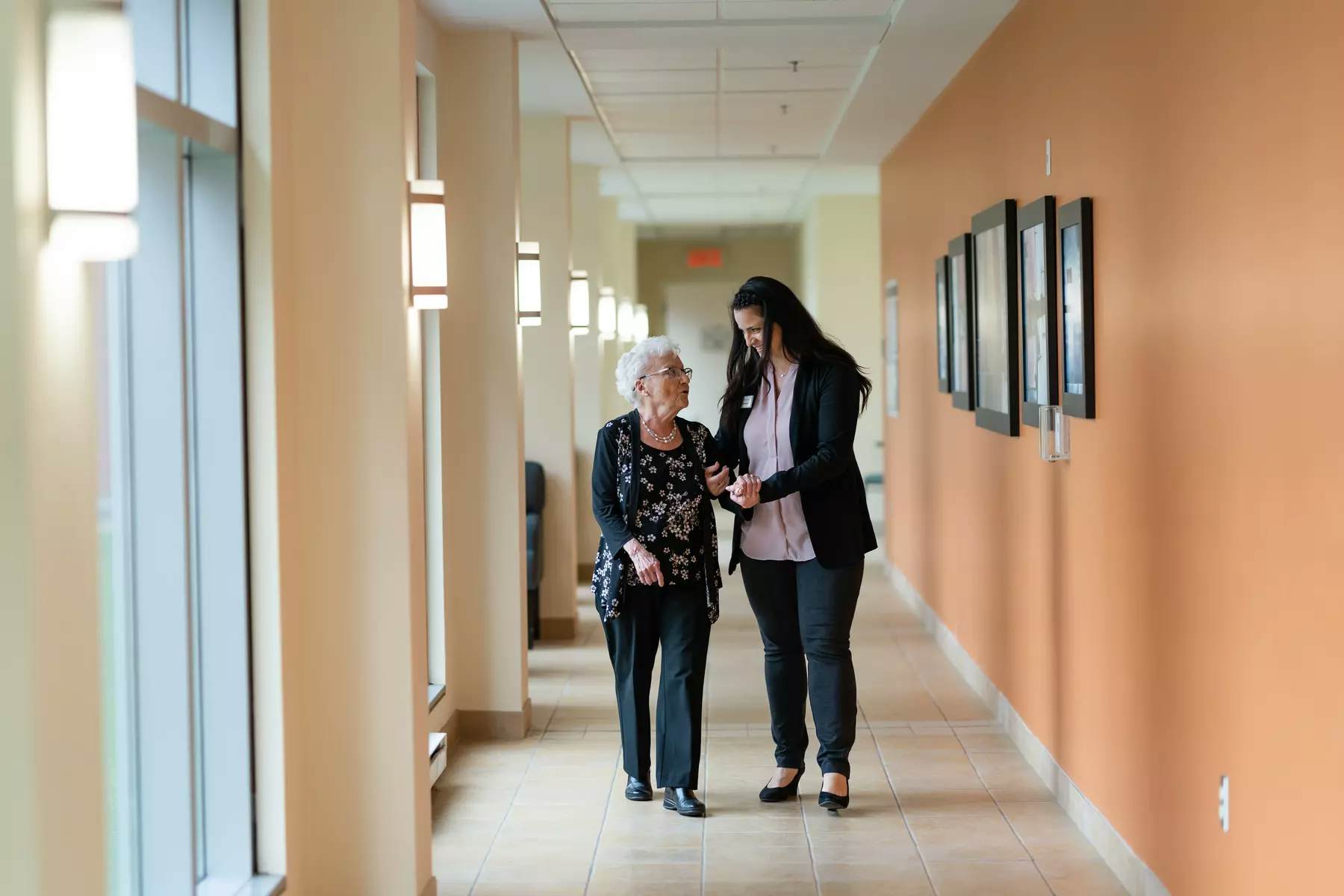 Chartwell care support staff helping a senior resident walk along the corridor