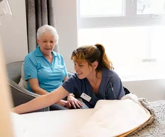 Chartwell staff helping the senior resident to make her bed