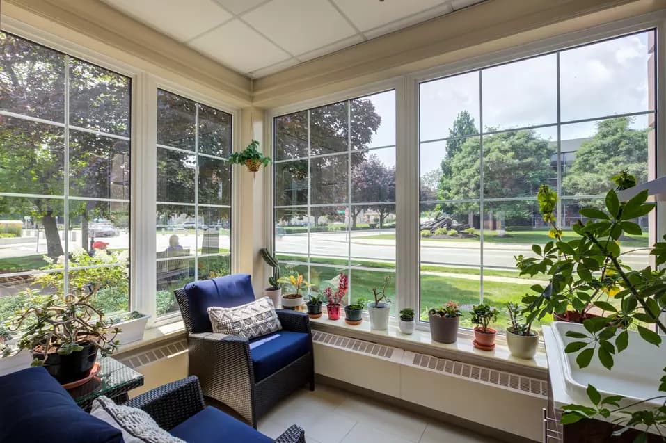 Bright sunroom with floor to ceiling windows at Chartwell Queen's Square Retirement Residence