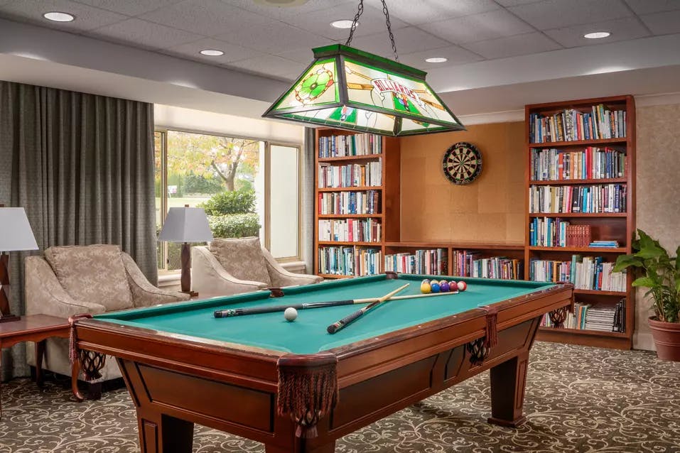 pool table lounge with chairs at chartwell crescent gardens retirement residence