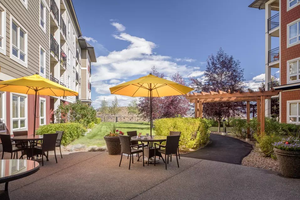 beautiful courtyard patio with patio furniture and umbrellas at chartwell ridgepointe retirement residence