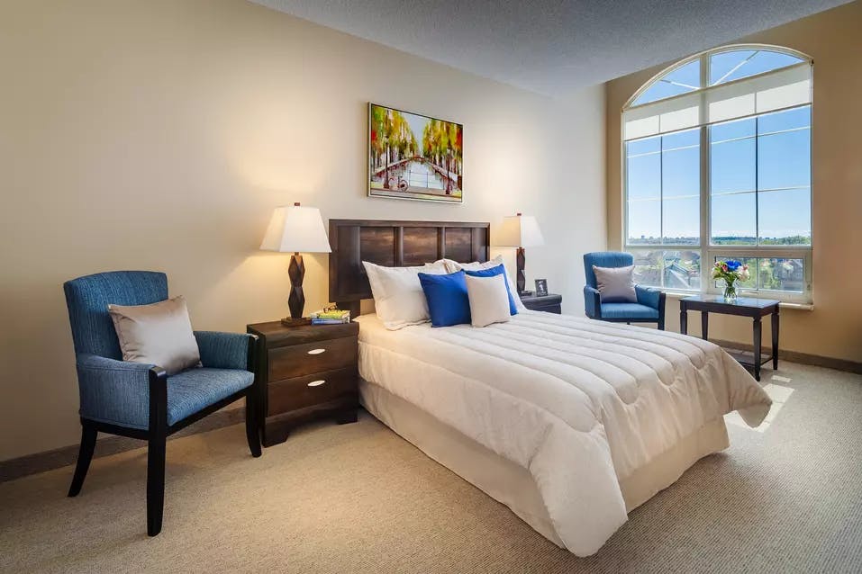 Suite bedroom with large windows at Chartwell Valley Vista Retirement Residence 