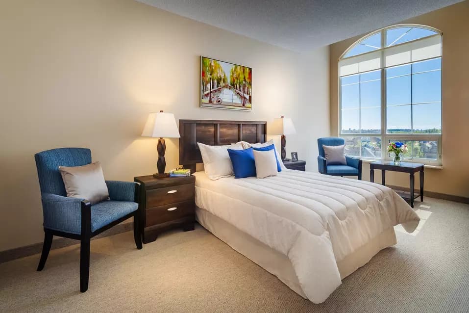 Suite bedroom with large windows at Chartwell Valley Vista Retirement Residence 