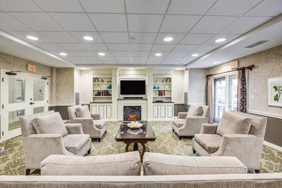 TV room with fireplace and comfortable couches at Chartwell Orchards Retirement Residence