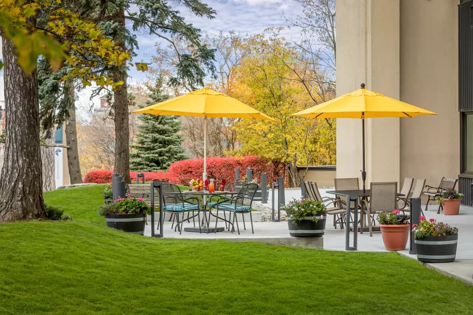 Walk out patio with greenspace and outdoor furniture at Chartwell Park Place Retirement Residence. 