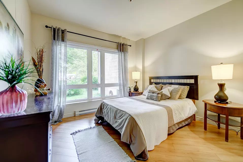 Chambre à coucher avec lit double bureau et grande fenêtre Chartwell Appartements de Bordeaux résidence pour retraités