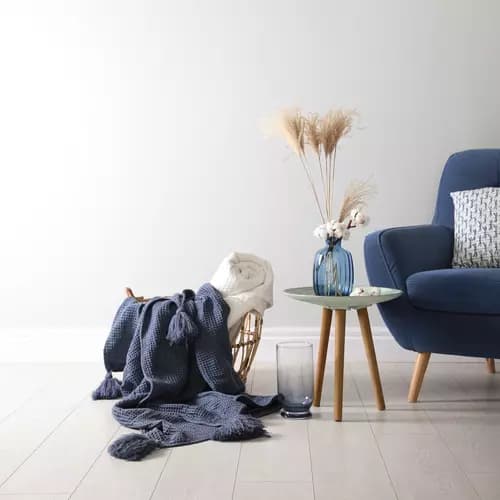 Livingroom with blue chair, side table and basket with knitted blanket. Salon avec chaise bleue, table d'appoint et panier avec couverture tricotée