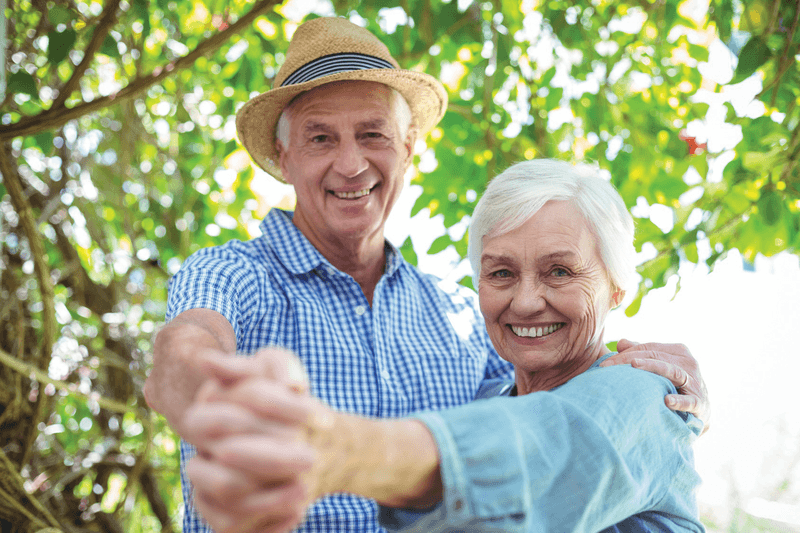 Senior couple dancing together outside.  Couple de seniors dansant ensemble à l'extérieur