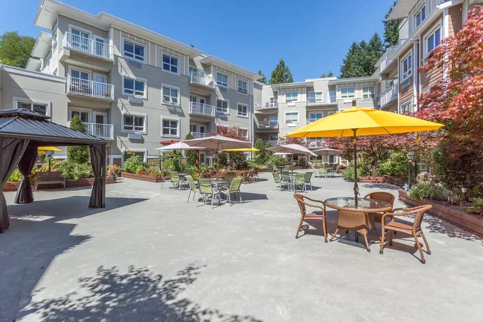 beautiful courtyard with patio furniture and umbrellas at chartwell cedarbrooke retirement residence