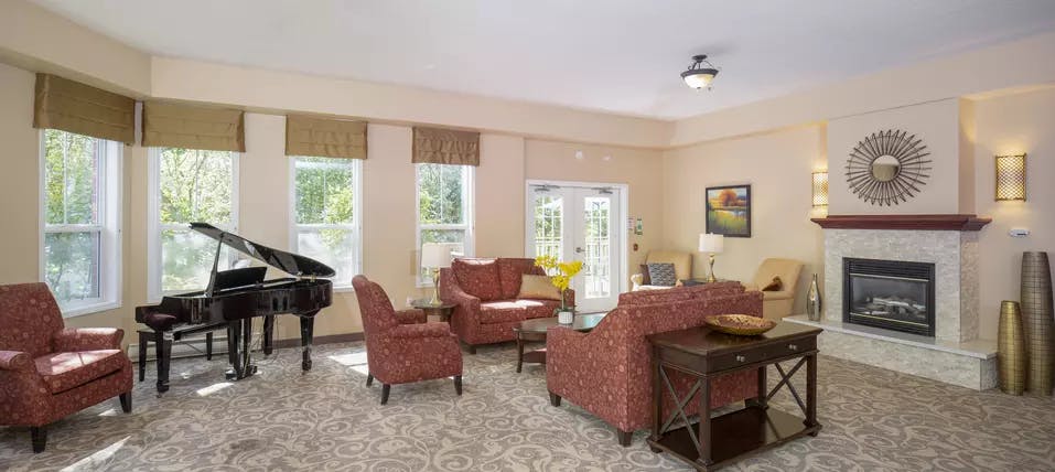 lounge with piano and fireplace at chartwell jackson creek retirement residence