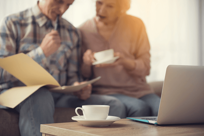 Senior couple blurred in the background with coffee cup in the foreground. Couple de seniors flou à l'arrière-plan et tasse de café au premier plan.