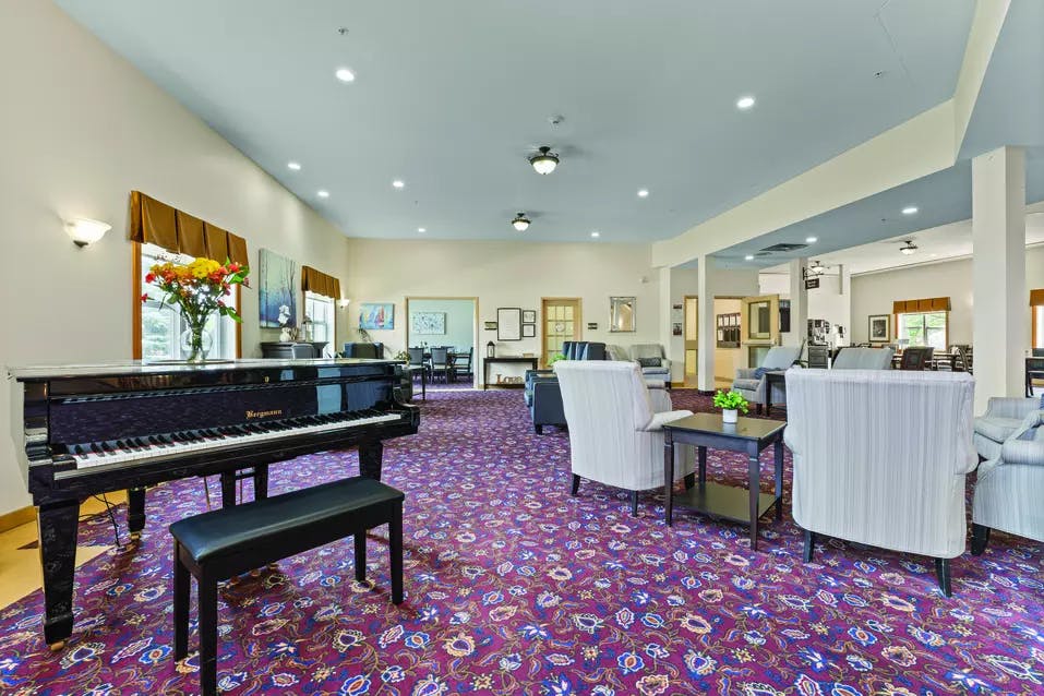 Lounge with piano and entertaining space at Chartwell Barton Retirement Residence.