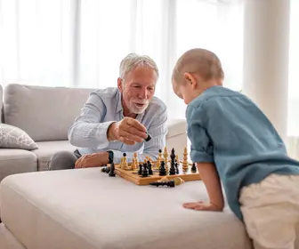 Senior man and his grandson is having a joyful time together while playing a chess / Un homme âgé et son petit-fils passent un moment joyeux ensemble en jouant aux échecs