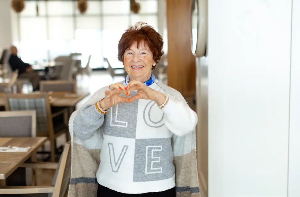 Joyful senior holding up a heart with her hands / Une personne âgée rayonnante de joie, formant un cœur avec ses mains