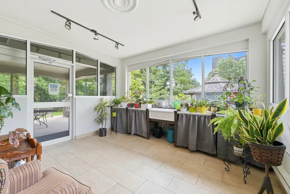 Sunroom with plants and garden views at Chartwell Riverside