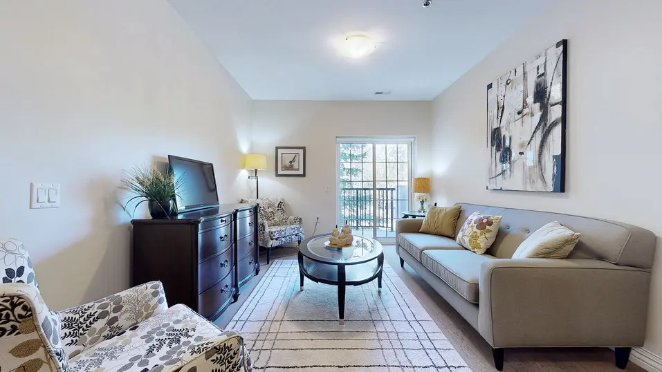Suite model with a grey couch, chair, table and tv at Chartwell Amherstburg