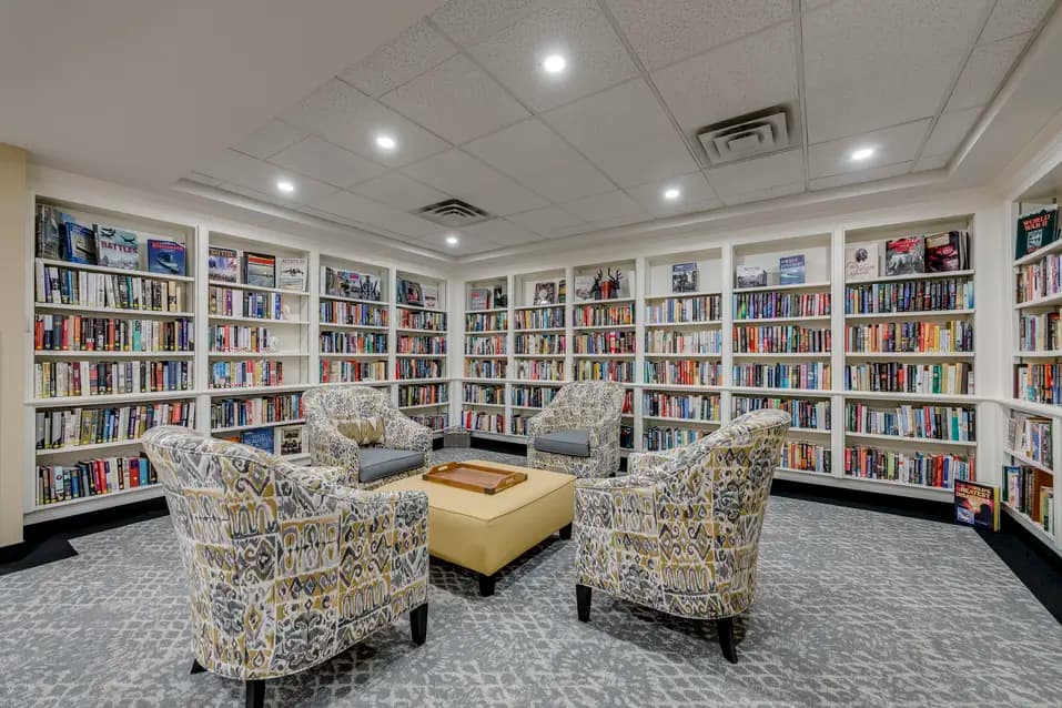 Library with bookshelves and comfortable reading chairs at Chartwell Welland / Bibliothèque avec étagères remplies de livres et fauteuils confortables à Chartwell Welland