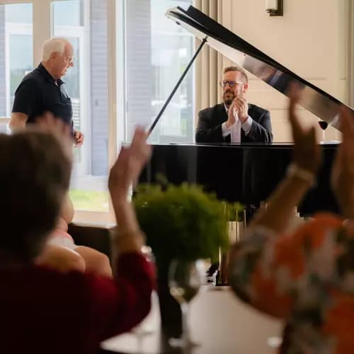 Senior residents applauding after a piano performance by a resident.