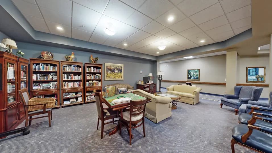 Library with bookcases, table and chairs at Chartwell Royal Oak Village