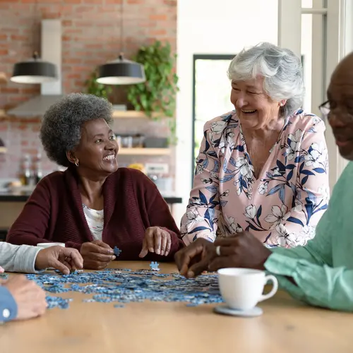 diverse group of seniors chatting and putting a puzzle together