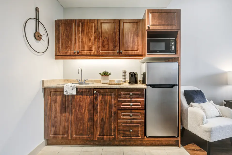 Model suite kitchenette with wood cabinetry and stainless-steel fridge at Chartwell ValleyVista / Cuisinette témoin avec armoires en bois et réfrigérateur en acier inoxydable à Chartwell ValleyVista