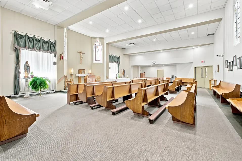 Intérieur de la chapelle avec bancs, autel et espace de culte au Chartwell Domaine Notre-Dame. / Chapel interior with pews, altar, and worship space at Chartwell Domaine Notre-Dame.