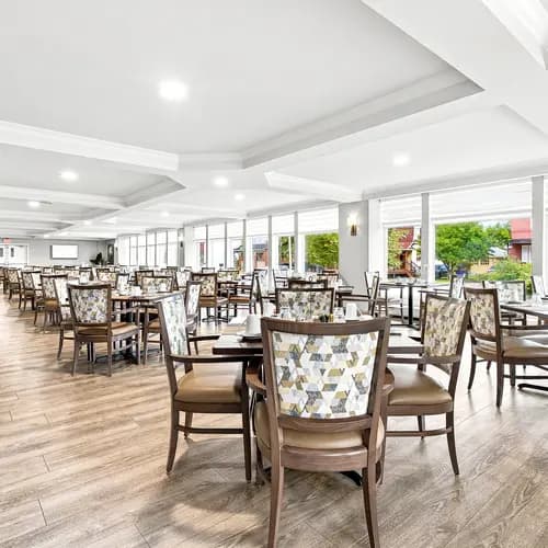Salle à manger lumineuse avec nombreuses places assises et grandes fenêtres au Chartwell Domaine Notre-Dame. / Bright dining room with ample seating and large windows at Chartwell Domaine Notre-Dame.