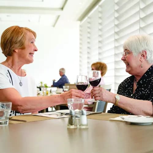 Residents enjoying a glass of wine together in the bright dining room at a Chartwell retirement residence / Résidents partageant un verre de vin dans la salle à manger lumineuse d’une résidence pour retraités Chartwell