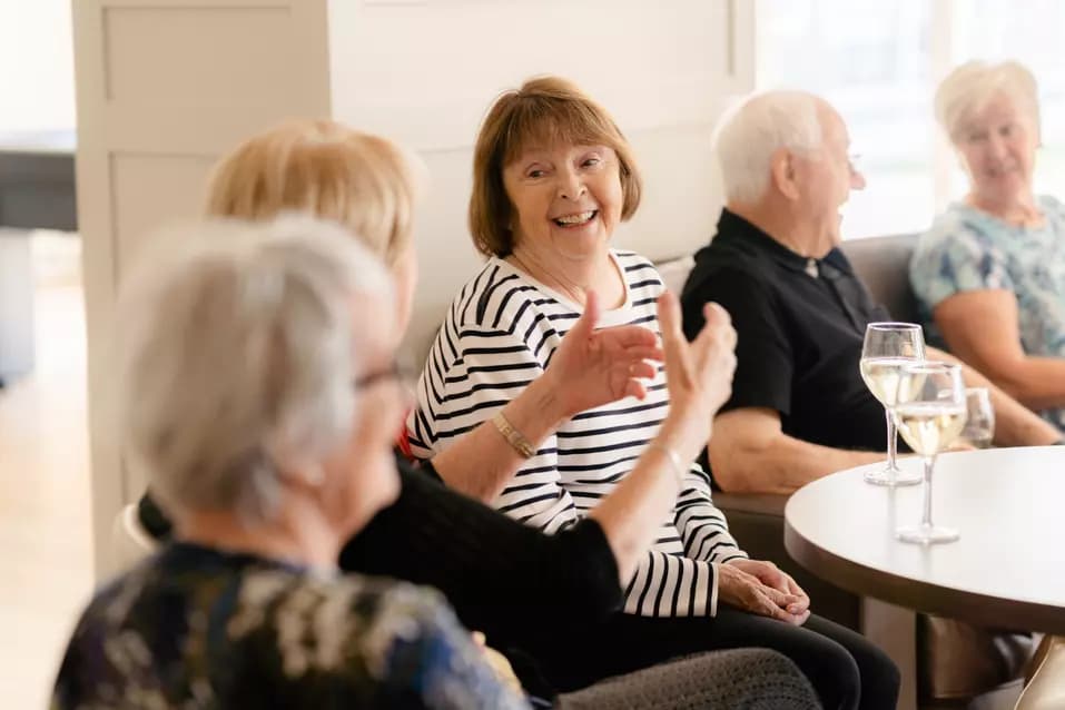 Senior residents chatting and enjoying a glass of wine