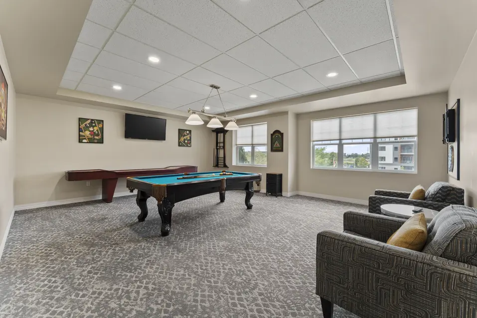 Billiards room with pool table and resident seating area at Chartwell Royal Oak Village. / Salle de billard avec table de billard et aire de détente au Chartwell Royal Oak Village.
