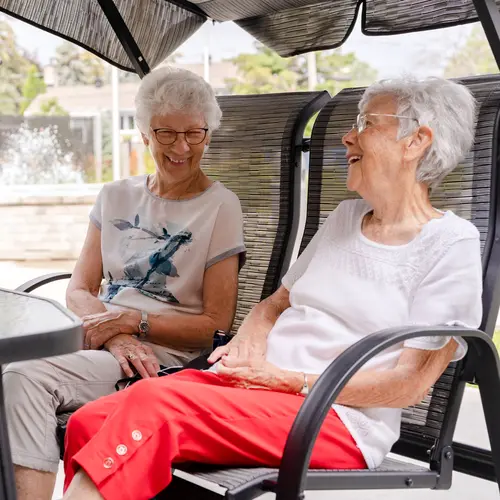 Chartwell senior residents chatting outside in lounge chair / Les résidents seniors de Chartwell discutent dehors, confortablement installés dans des fauteuils