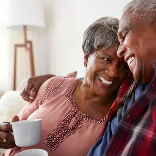 A loving senior couple hugs each other in a cozy couch / Un couple de seniors amoureux se serre l'un contre l'autre dans un canapé confortable