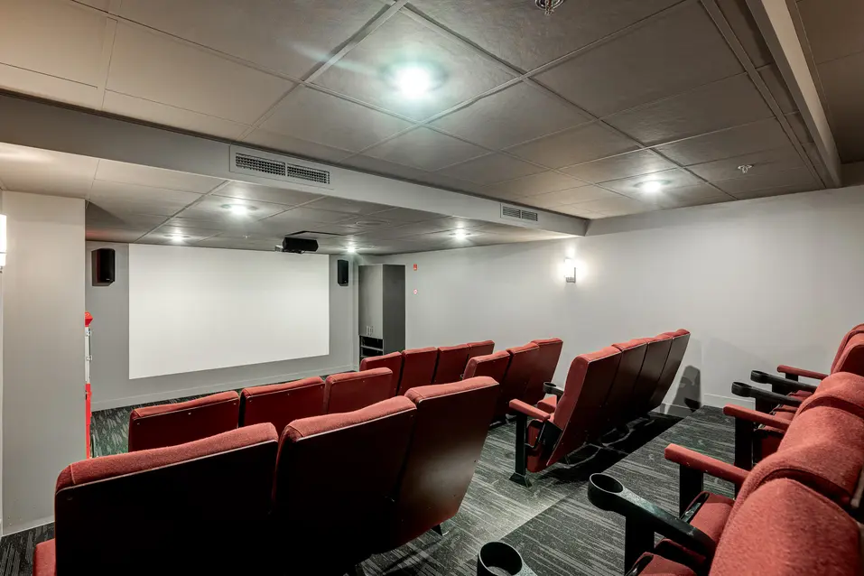 Rendu de rénovation de la salle de cinéma privée avec sièges en gradins à Chartwell Des Rivières / Private theatre renovation rendering with tiered seating at Chartwell Des Rivières