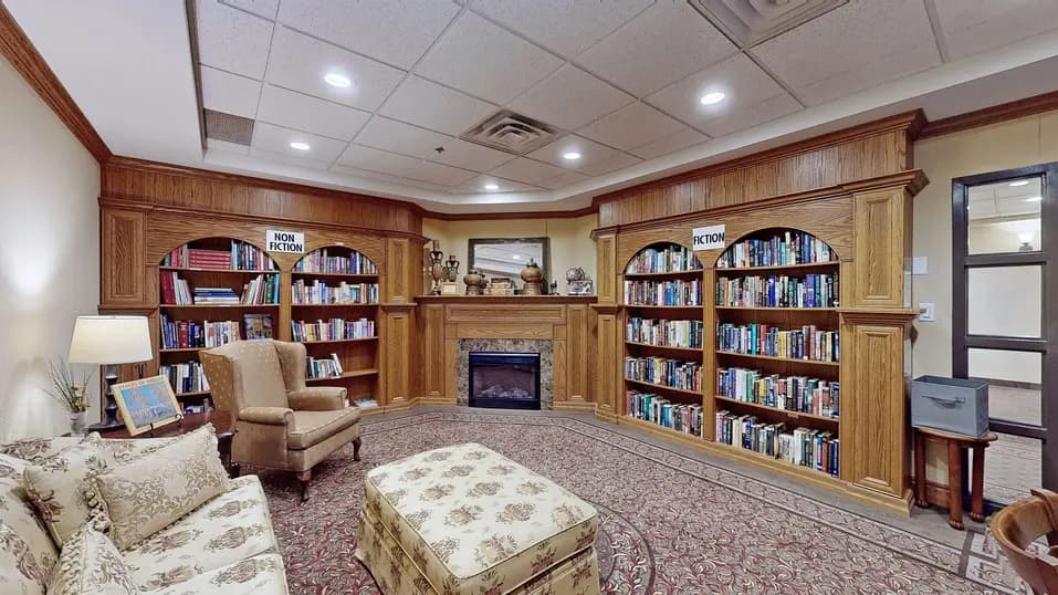 Library with couch and wingback chair at Chartwell Amherstburg