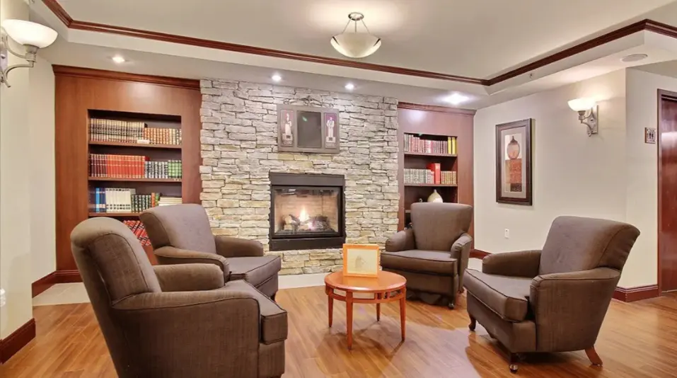 Salon chaleureux avec foyer en pierre et bibliothèque à Chartwell Manoir Archer / Cozy lounge with stone fireplace and bookshelf at Chartwell Manoir Archer