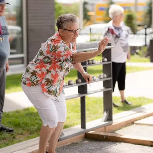 Senior resident throwing Bocce ball while the other look over her