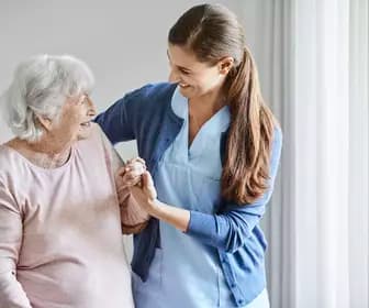 Care giver gently guides senior woman with a kind smile / L'aide-soignante accompagne délicatement la personne âgée avec un sourire bienveillant