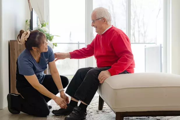 Chartwell Care Staff helping the senior resident wearing shoes / Le personnel de Chartwell Care aide la résidente âgée à porter des chaussures