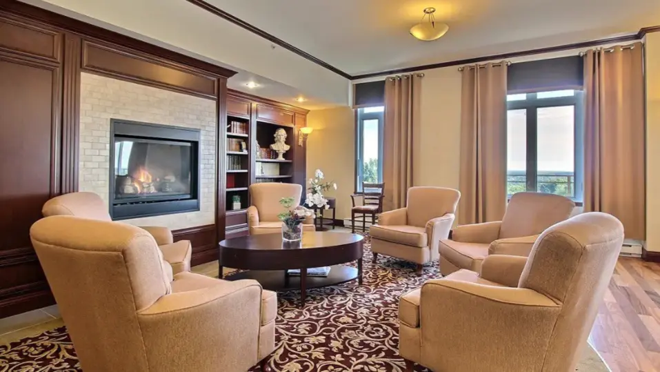 Salon élégant avec foyer et fauteuils confortables à Chartwell Manoir Archer / Elegant lounge with fireplace and comfortable armchairs at Chartwell Manoir Archer
