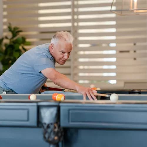 Senior man focusing on a white ball while playing the pool