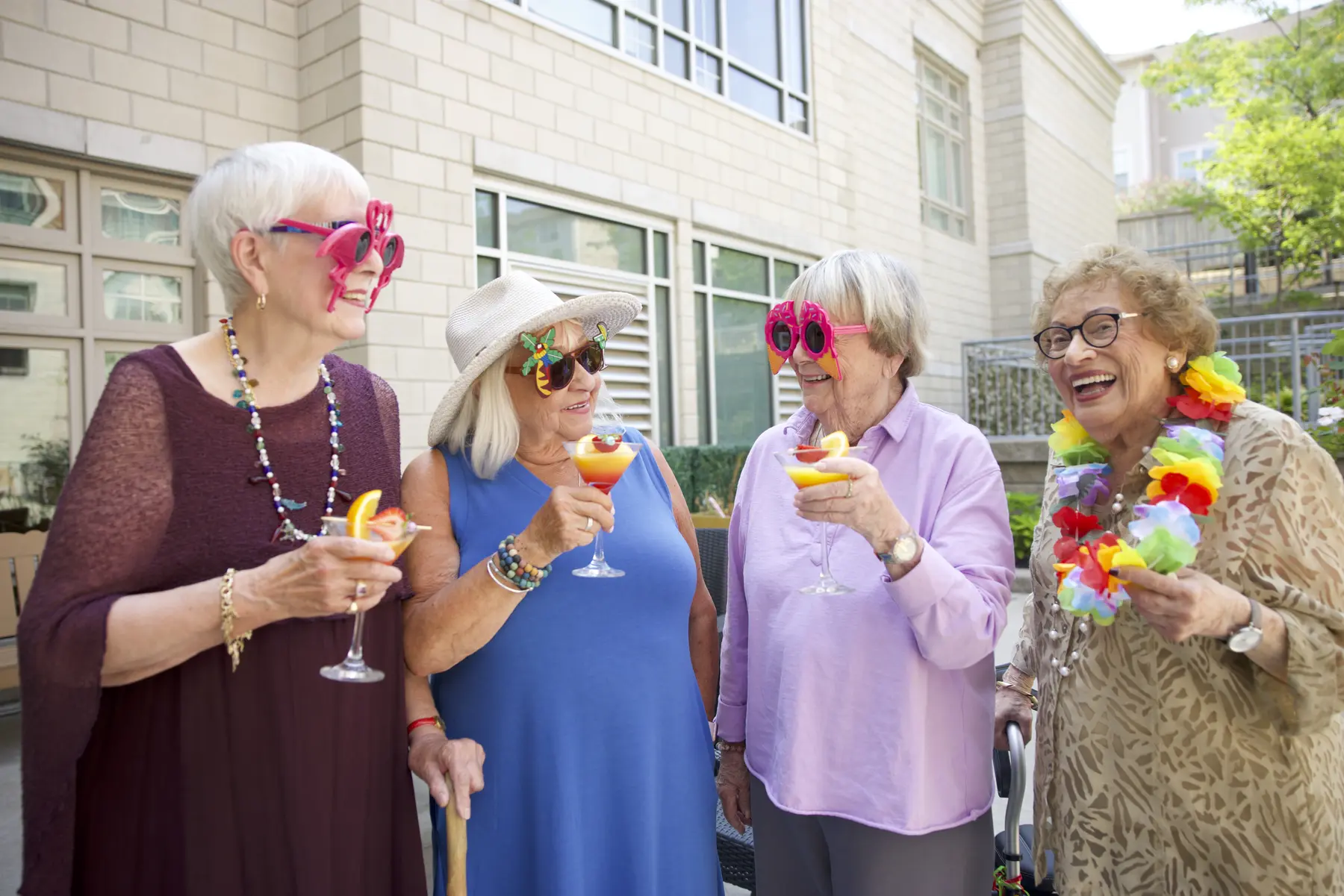 A group of senior women wearing fun glasses are having fun while drinking at Chartwell Residence / Un groupe de femmes âgées portant des lunettes amusantes s'amusent tout en buvant à la résidence Chartwell