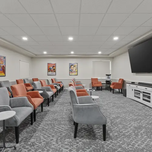Theatre room with rows of seating and large presentation screen at Chartwell Royal Oak Village. / Salle de cinéma avec rangées de sièges et grand écran de présentation au Chartwell Royal Oak Village.