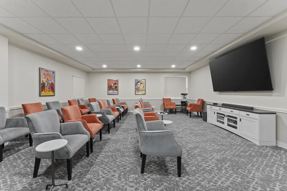 Theatre room with rows of seating and large presentation screen at Chartwell Royal Oak Village. / Salle de cinéma avec rangées de sièges et grand écran de présentation au Chartwell Royal Oak Village.