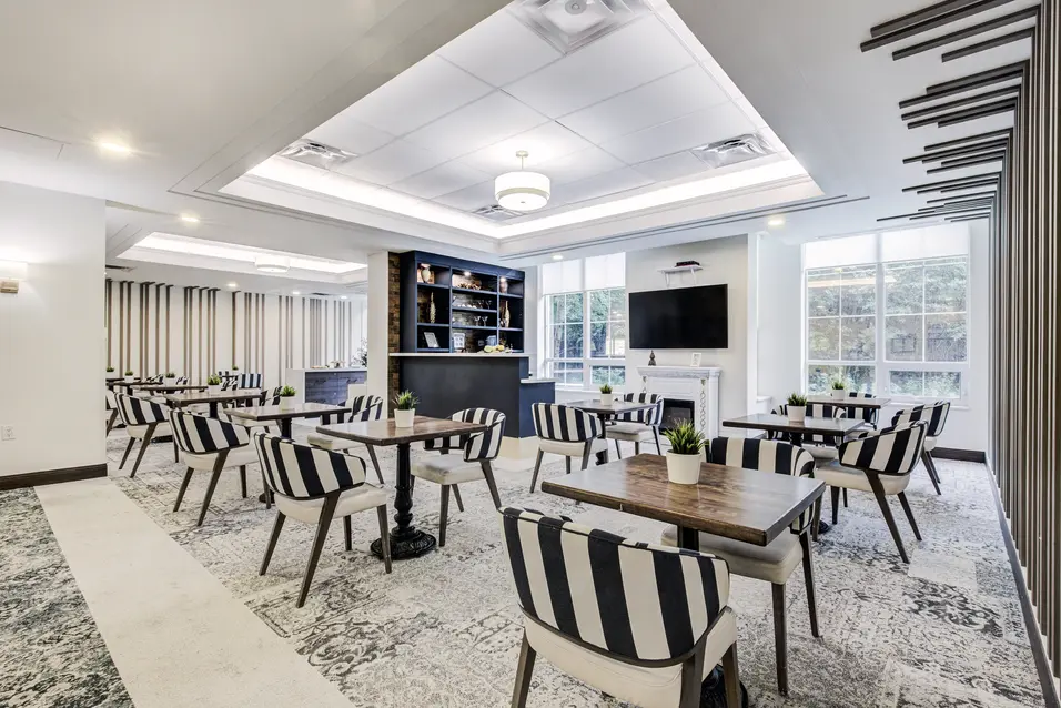 Modern bistro with café seating and fireplace lounge at Chartwell ValleyVista / Bistro moderne avec tables café et coin détente avec foyer à Chartwell ValleyVista