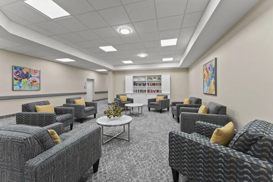 Resident library lounge with comfortable seating and gathering space at Chartwell Royal Oak Village. / Bibliothèque et salon des résidents avec sièges confortables et espace de détente au Chartwell Royal Oak Village.