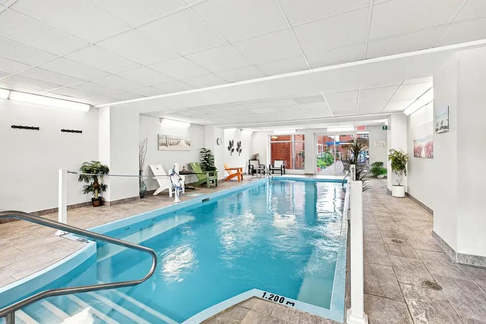Piscine intérieure avec accès sécurisé et espace de détente au Chartwell Cité-Jardin. / Indoor swimming pool with accessible entry and relaxation area at Chartwell Cité-Jardin.
